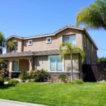 Photo of a Los Angeles sober living with green grass, palm trees, and flowers.